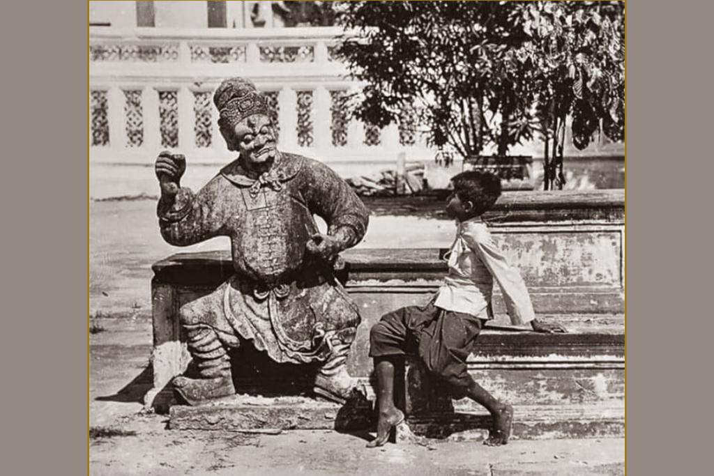 ภาพถ่ายเมื่อปี พศ.๒๔๖๐ เด็กชายกับตุ๊กตาจีน ในบริเวณพระอุโบสถ วัดอรุณราชวรารามราชวรมหาวิหาร